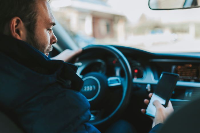 Man checking phone while driving.